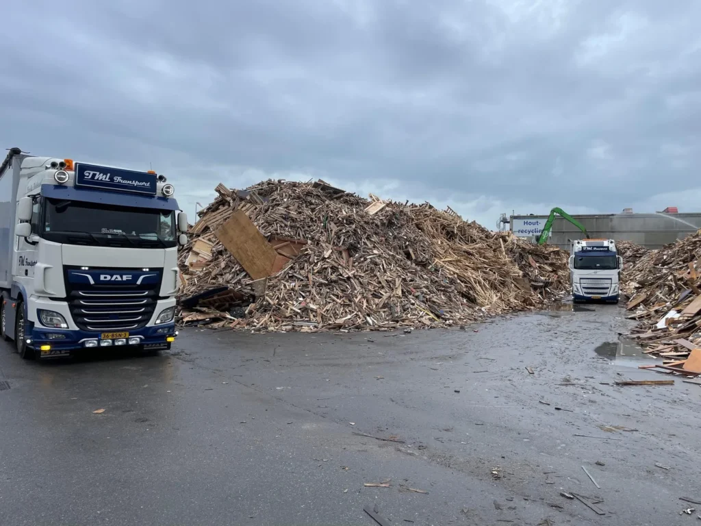 DAF vrachtwagen van TML Transport bij een berg houtafval op een recyclinglocatie