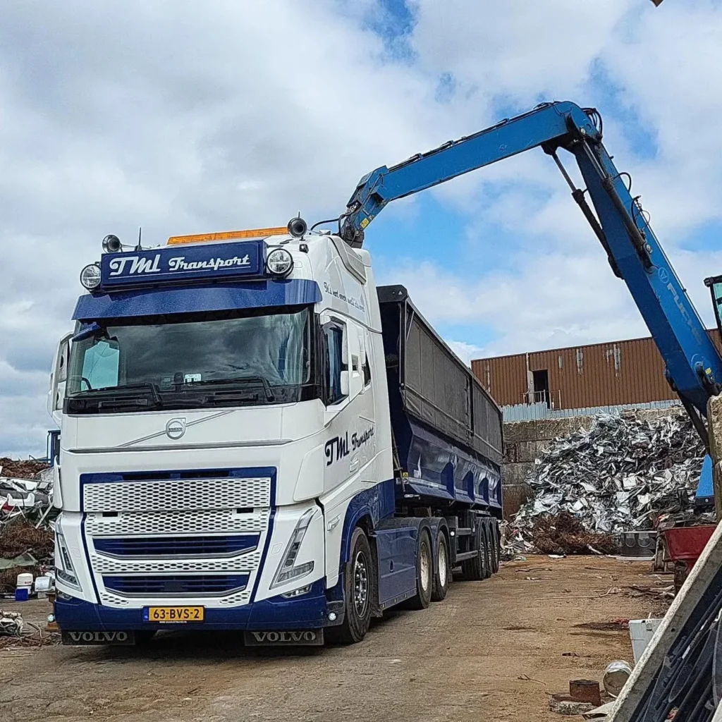 Volvo kippercombinatie van TML Transport wordt geladen met schroot door een overslagkraan